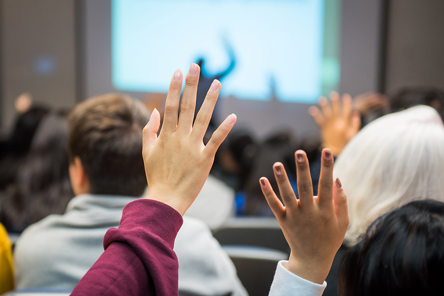 Students raided hands in a classroom setting.