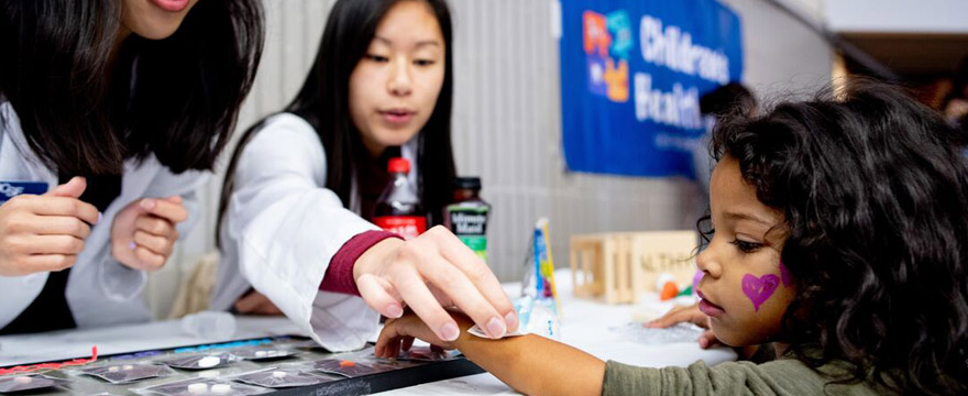 Students and child at a UCSF School of Dentitry table event